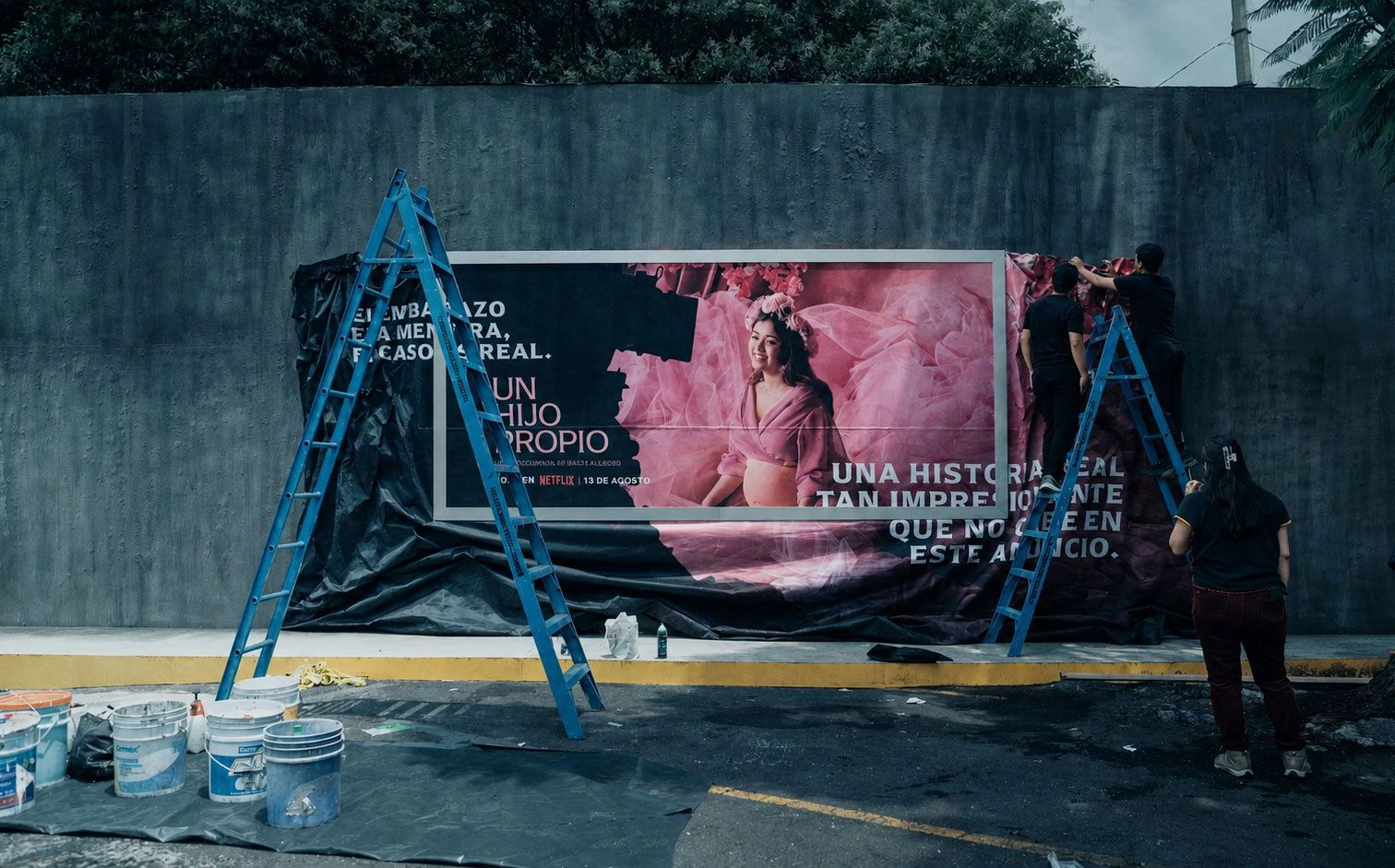 Equipo instalando la campaña OOH de Netflix para Un hijo propio con una gran tela impresa que se extiende alrededor del anuncio principal.
